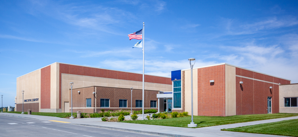 View of Adams Central Elementary front entrance on a sunny day, showing a variety of surface treatments